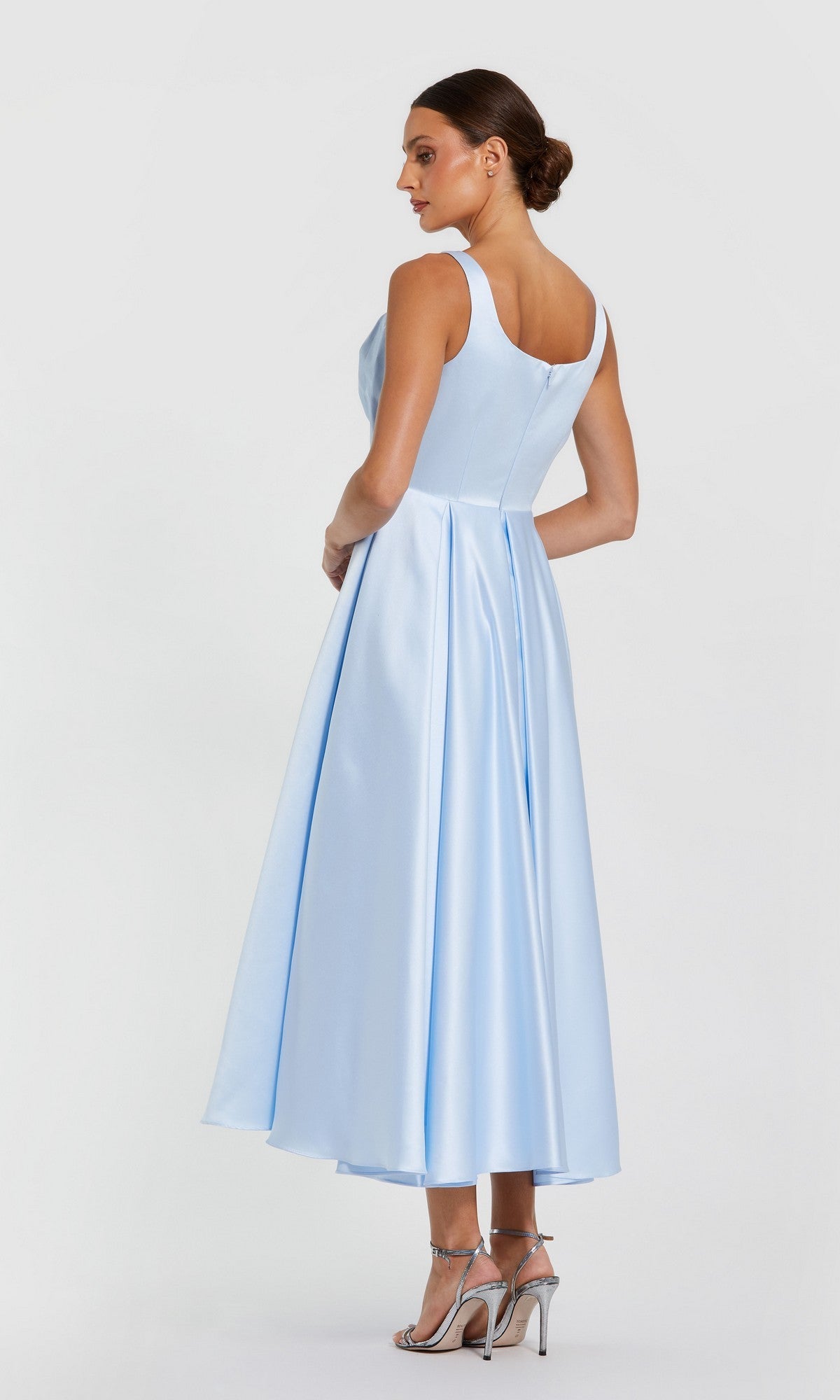A woman in profile wears the Mac Duggal 2288 midi wedding guest dress—a sleeveless, light blue satin A-line with a fitted bodice and flared skirt—paired with high-heeled sandals, perfect for elegant occasions.